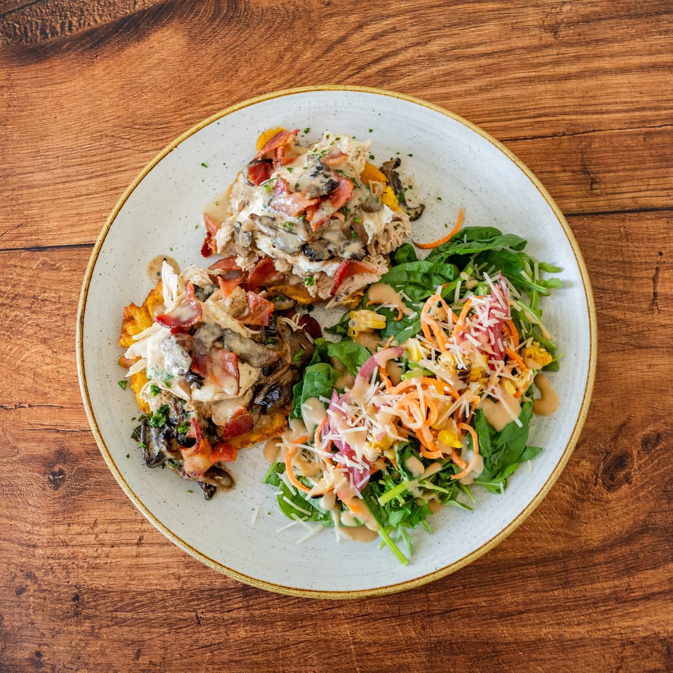 A plate of chicken and mushroom with bacon, served with a fresh green salad.