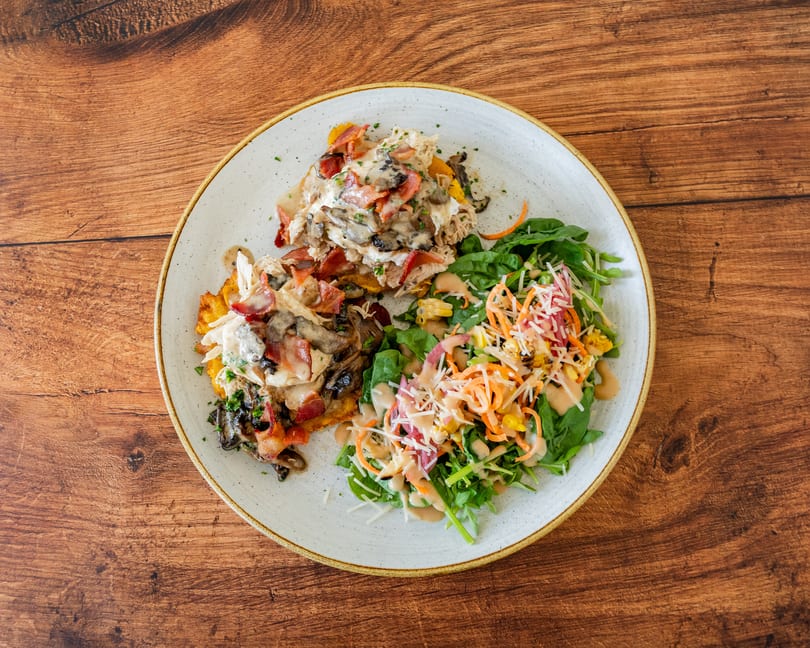 A plate of chicken and mushroom with bacon, served with a fresh green salad.